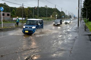 大雨で冠水した道道を通行する車＝５日午前９時２０分、北広島市（綱島康之撮影） 