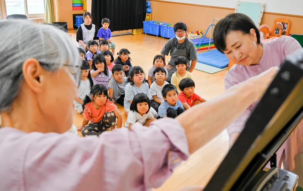 おはなしサークル「ど・れ・み」のメンバーがパネルで紹介する物語に見入る園児たち
