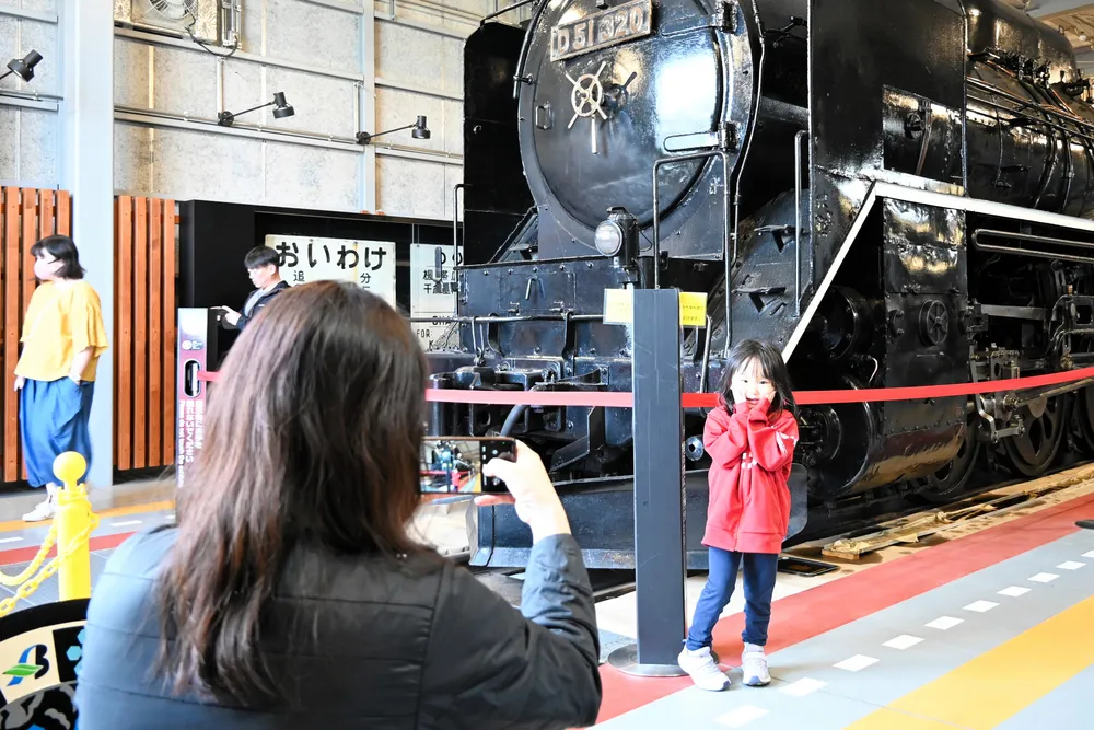 蒸気機関車（SL）の前で写真を撮る親子連れ