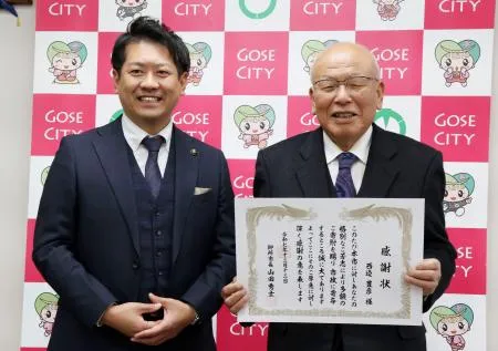 奈良県御所市役所で山田秀士市長（左）から感謝状を受け取った西辺豊彦さん=12日午後