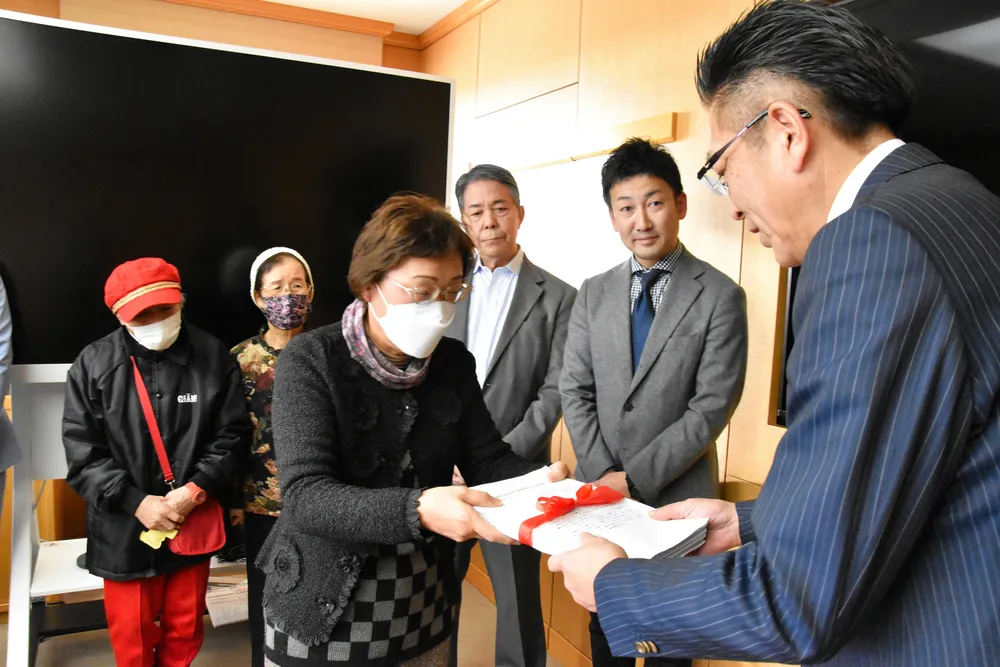 福祉利用割引券の経過措置を求める署名を小鷹副市長に手渡す市民の会の山崎代表（中央）