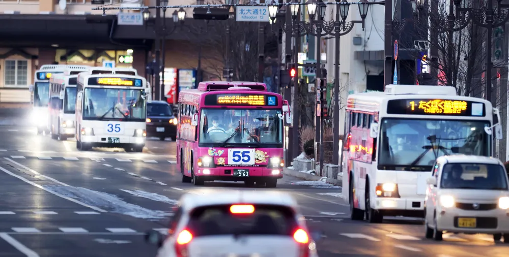 夕暮れ時の釧路市中心部を連なって走る路線バス。住民の足として地域を支える=2024年12月28日（小川正成撮影）