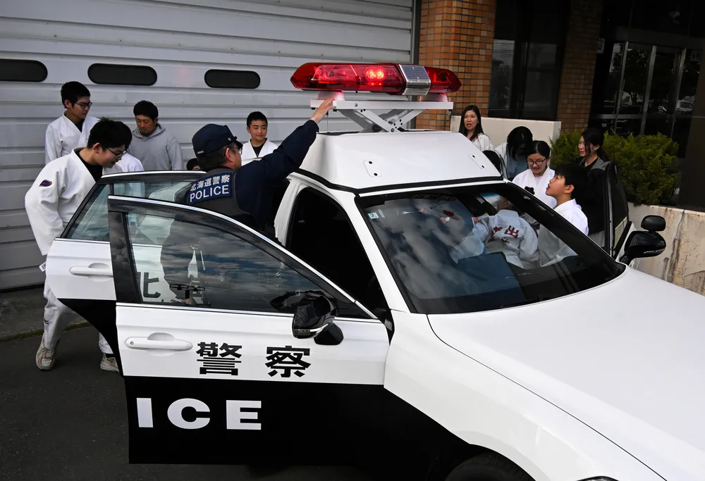 栗山署員からパトカーの説明を受ける栗山町柔道スポーツ少年団の子どもたち
