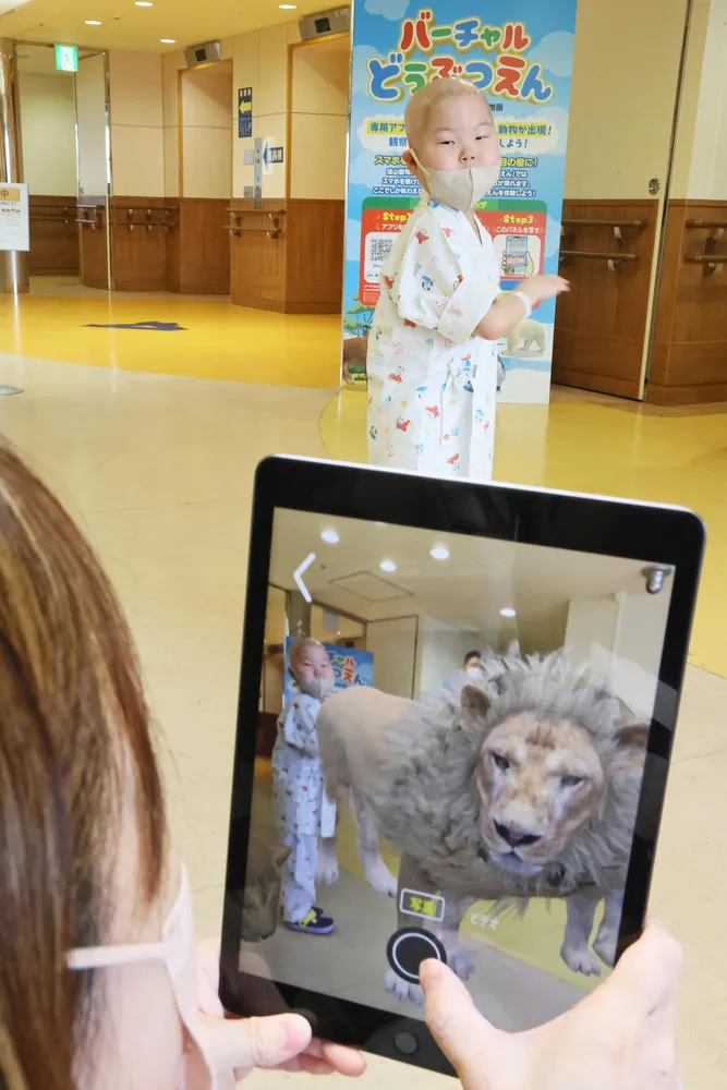 画面に現れたライオンと記念写真に納まる入院中の子ども（奥）=伊丹恒撮影
