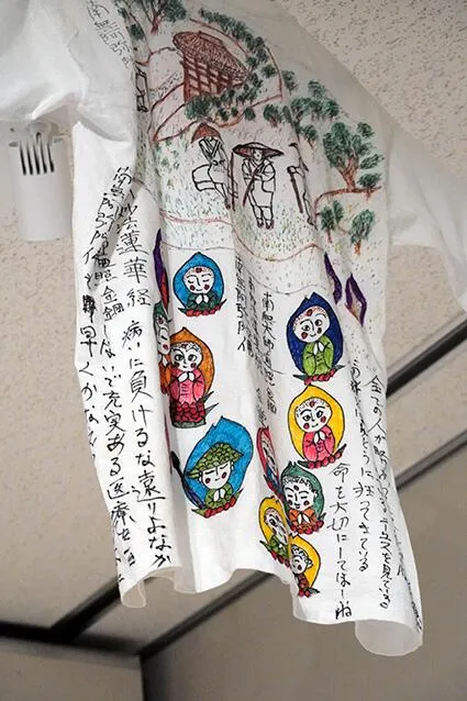 布のTシャツにサインペンなどで仏教の経典の言葉やお遍路などが描かれた作品