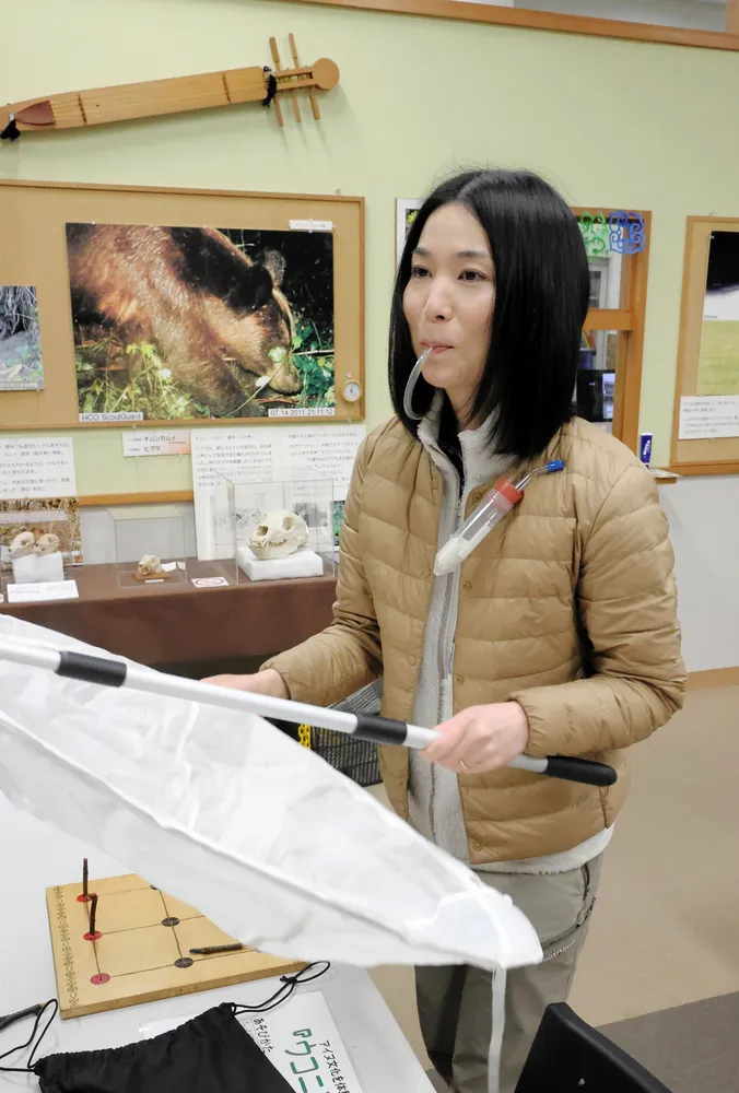 吸虫管をくわえ、手にはネットを持って虫の採集方法を説明する伊藤彩子さん