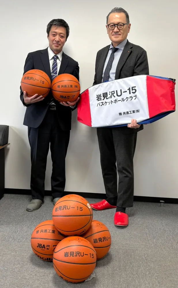 岩見沢バスケットボールクラブU-15の黒川広佳監督（左）にボールなどの購入費を寄付した新川勝久社長。地域でチームを支えている