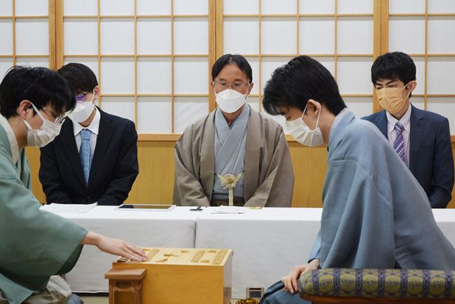 王位戦第２局２日目の朝、藤井聡太王位（手前右）と豊島将之九段（同左）が駒を並べるのを見守る立会人の深浦康市九段＝７月１４日午前９時ごろ、札幌市南区定山渓温泉の「ぬくもりの宿ふる川」（文化部　大原智也撮影）