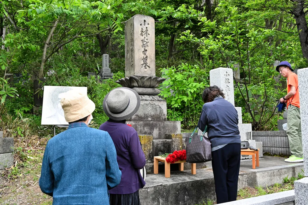 多喜二が眠る墓の前で手を合わせる参加者