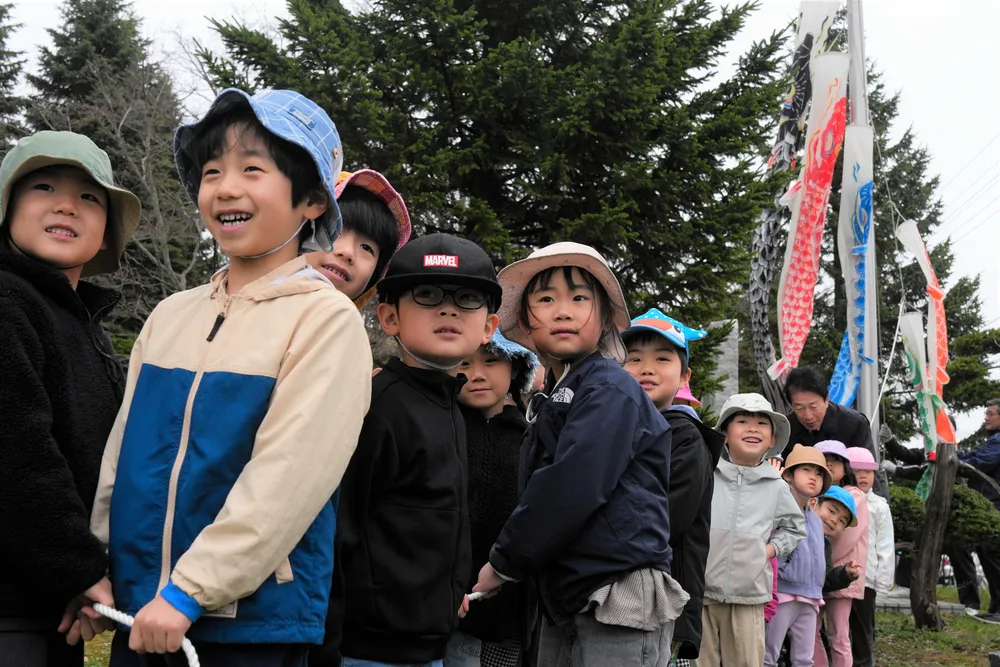 笑顔でひもを引っ張ってこいのぼりを揚げる中央保育所の子どもたち