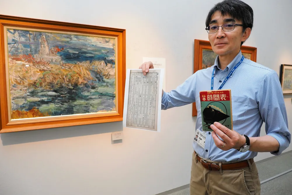 古い時刻表を手に納沙布岬を描いた油絵を紹介する岡部館長