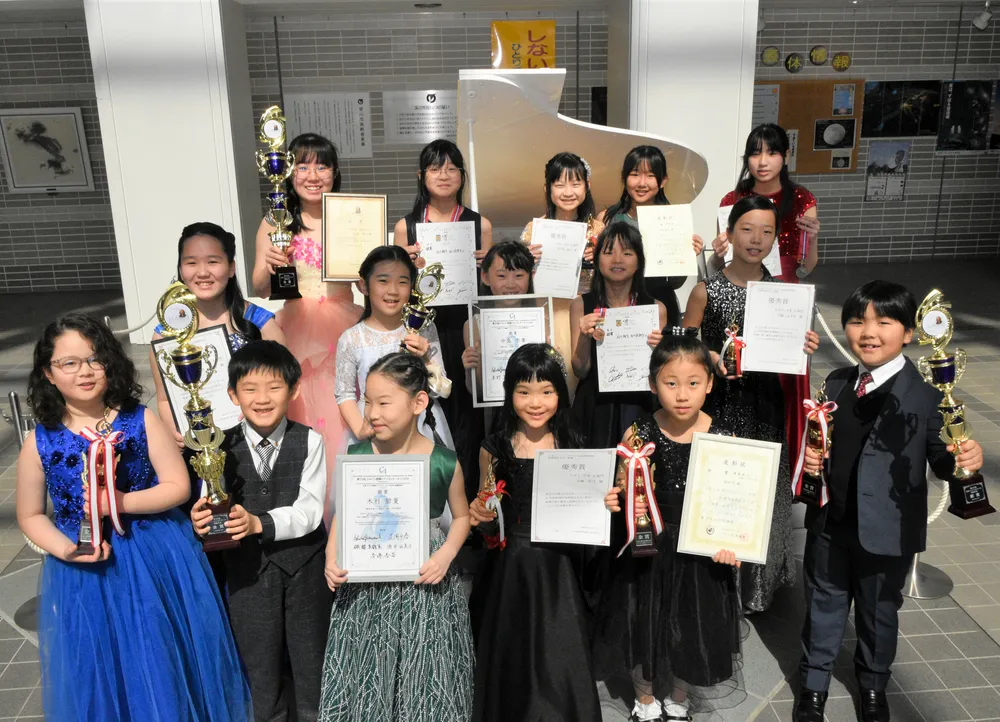 コンクールのトロフィーや表彰状を手に、受賞を喜ぶ子どもたち