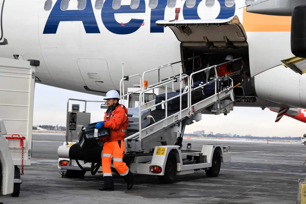 新千歳空港に到着した韓国便から、手荷物を運び出すFMG関連会社の従業員=昨年12月