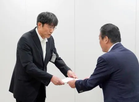 国交省九州運輸局からの改善を指示する文書を受け取る熊本市の井芹和哉交通事業管理者（左）=18日午後、福岡市