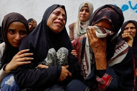 イスラエル軍の攻撃により犠牲になった息子の靴を抱え、死を悼む母親ら=8月、ガザ北部ガザ市（ロイター=共同）