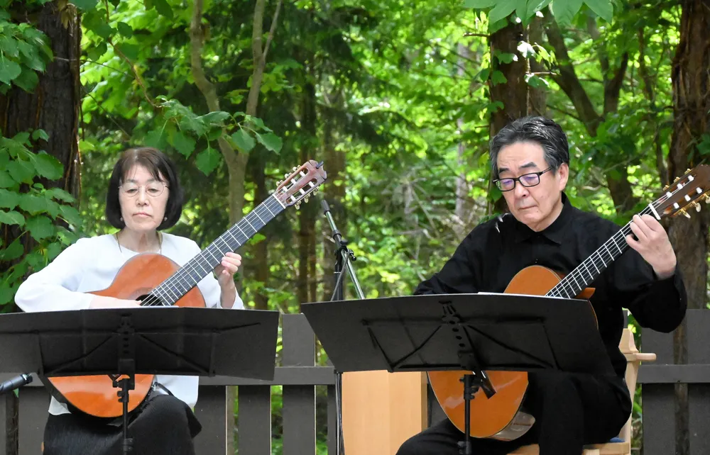 緑に囲まれた会場でギターの音色を響かせる山崎さん夫妻