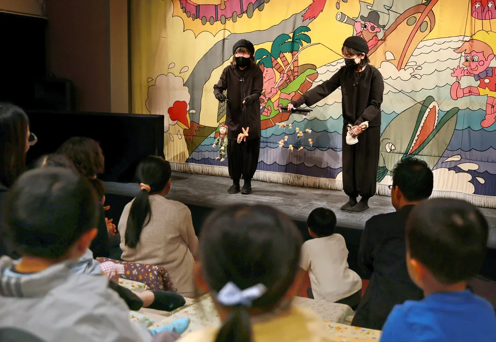 こぐま座の舞台で人形劇を上演した後、子供たちに人形を見せる市民劇団=5月24日（畠中直樹撮影）