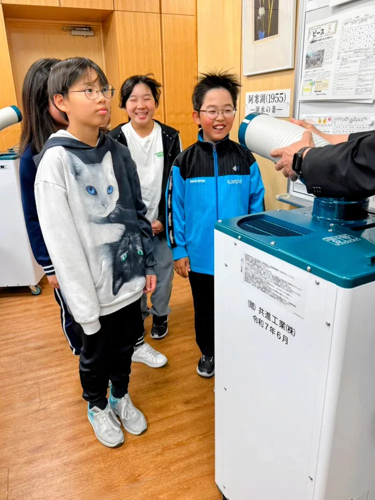寄贈されたスポットクーラーの風力を試し、笑顔を見せる岩見沢小の児童たち