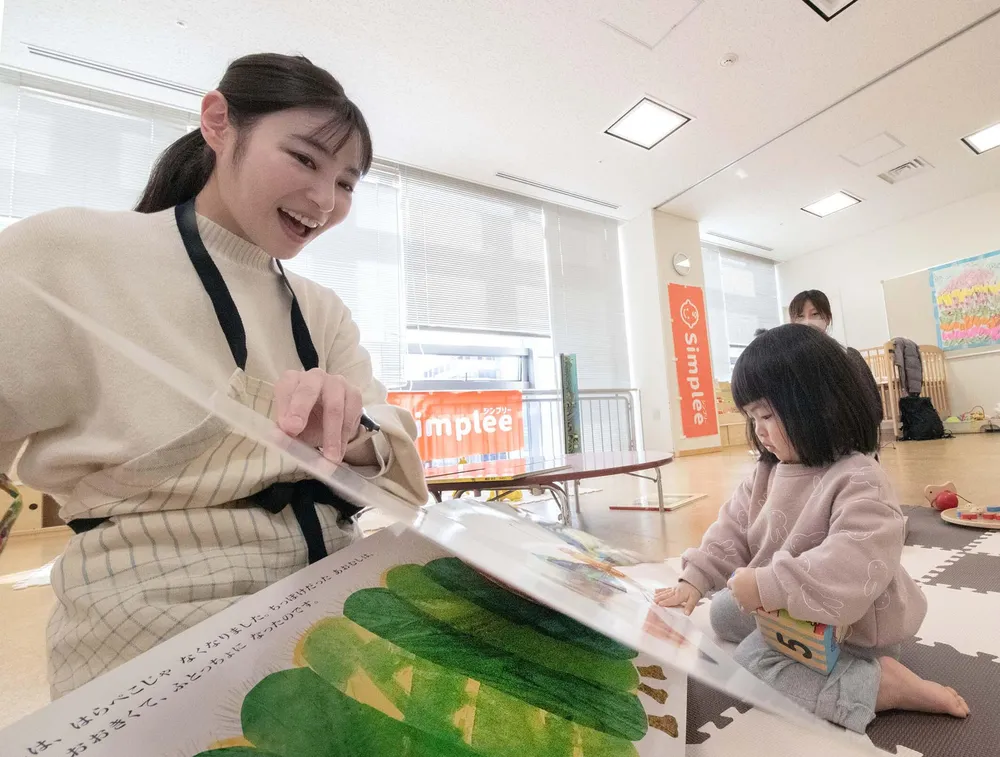 札幌のイベントで設けた託児スペースで、預かった子どもに絵本を読む「シンプリー」の諏訪実奈未さん（左）=植村佳弘撮影