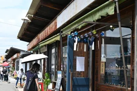 青果市場だった長屋を改装した「沼垂テラス商店街」の店舗。旧店舗の看板が昭和レトロな雰囲気を醸し出す=2025年7月、新潟市