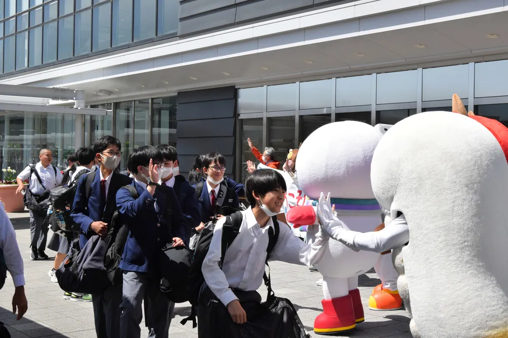 新函館北斗駅で出迎えたゆるキャラとハイタッチする修学旅行生たち