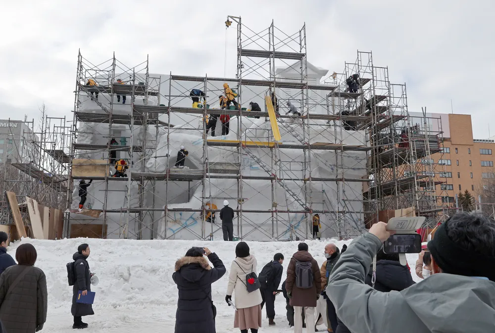 見学会の参加者たちが見守る中、製作が進められる大雪像（浜本道夫撮影）