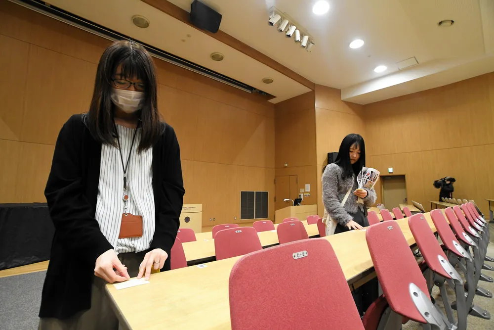 北海道大学の試験会場で、机に受験番号のシールを貼る職員