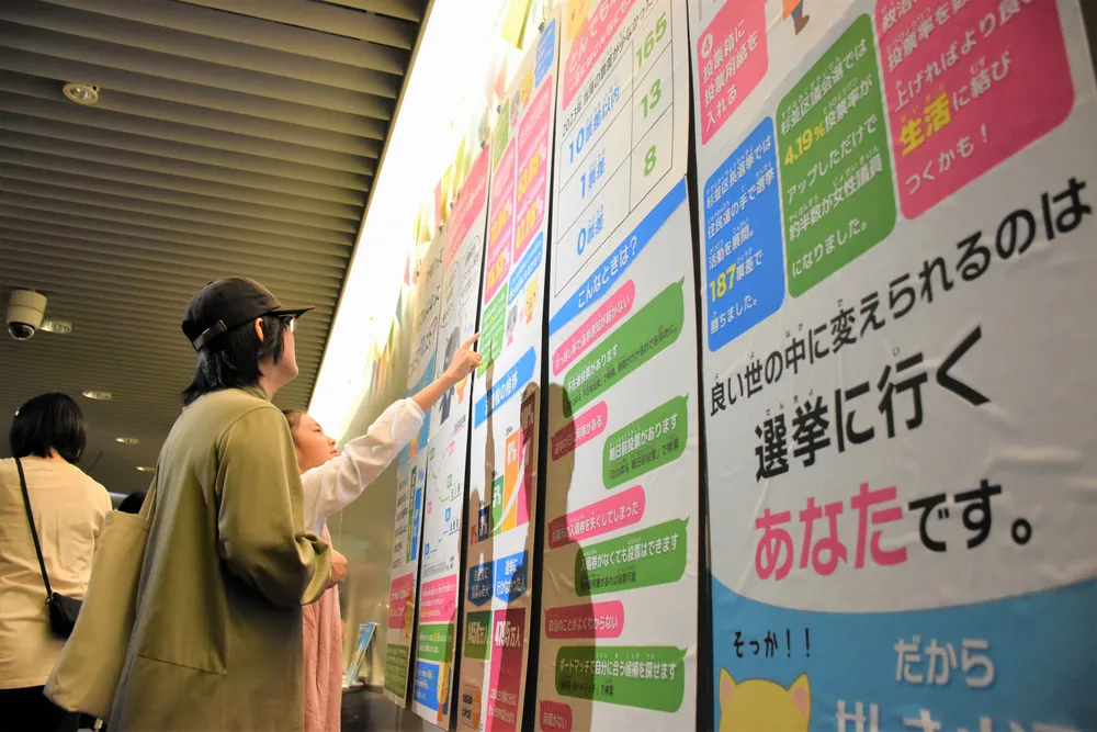 「投票フェス」のパネル展示を見て、選挙の仕組みを学ぶ人々