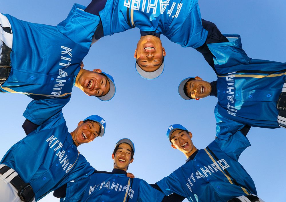 日本ハムのビジターユニホームに似た青色の練習着で笑顔を見せる野球部３年生。ＯＢ・ＯＧ会が寄贈した（野沢俊介撮影） 