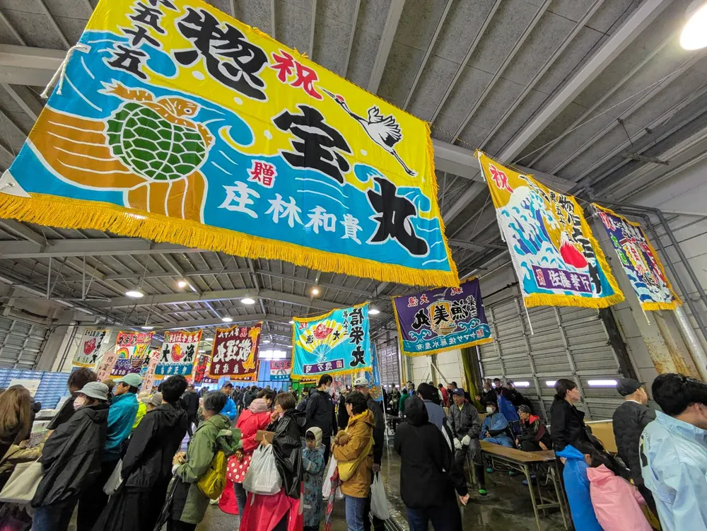 大漁旗が飾られたまつり会場で行列をつくる人たち