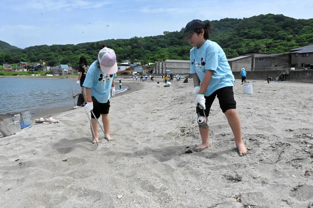 砂浜に落ちたごみを拾う子どもたち