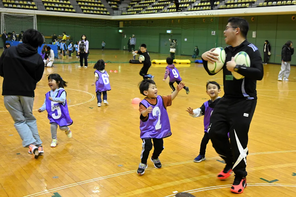 ラグビーボールを持ったスタッフを追いかける子どもたち
