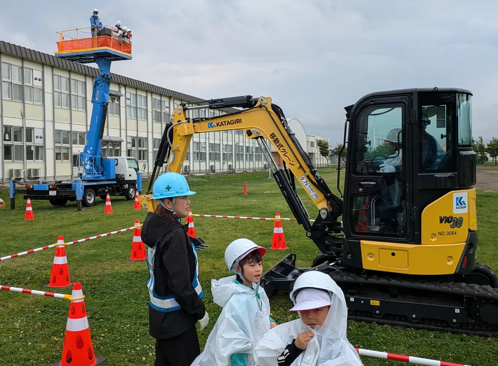 ショベルカーに乗る順番待ちをする新篠津小の児童。奥は児童を乗せた高所作業車