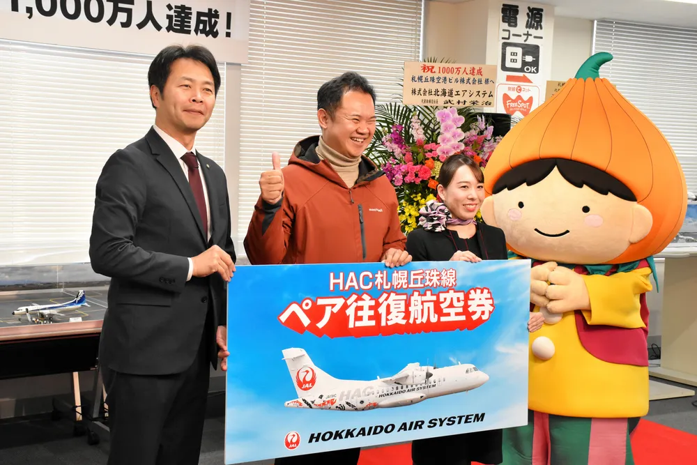１千万人目の利用客となり、ペア往復航空券など記念品を受け取るタナワット・ローポンピパットさん（中央）