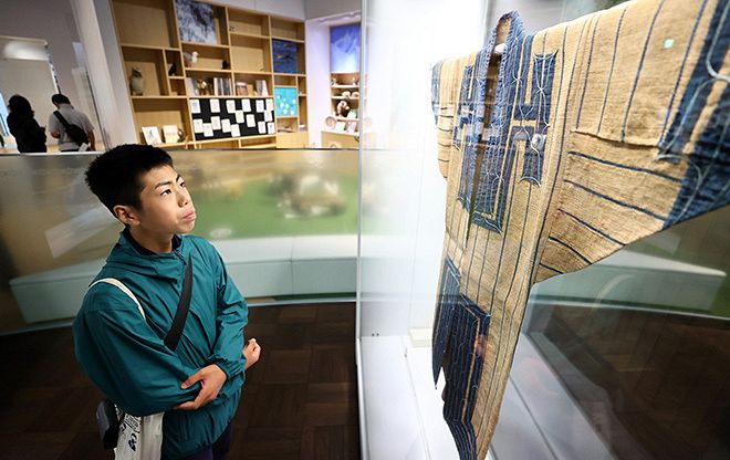 国立アイヌ民族博物館で着物を眺める小川さん（井上浩明撮影）