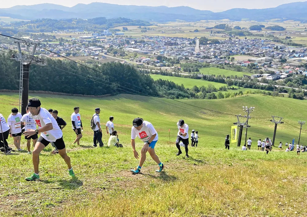 ゲレンデを駆け上がりゴールを目指す「ヒガシヤマ500」の参加者=昨年9月、和寒東山スキー場