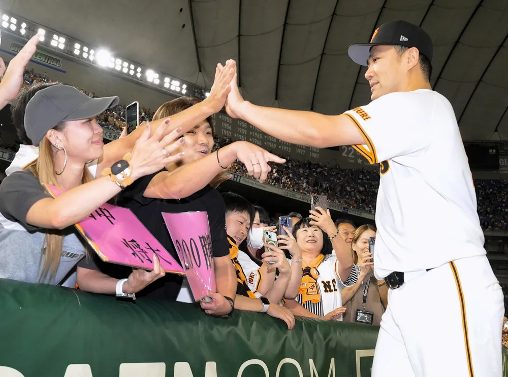 日米通算200勝を達成し、ファンとタッチを交わす巨人・田中将=東京ドーム