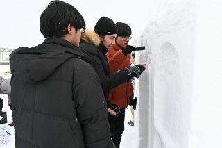 雪の礼拝所の装飾部分を彫り進めるメンバー 