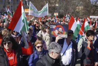 ハンガリーの首都ブダペストで、ウクライナのゼレンスキー大統領らの顔写真と共に「戦争をやめろ」と記したプラカードを掲げて行進するフィデス支持者ら=3月（共同）