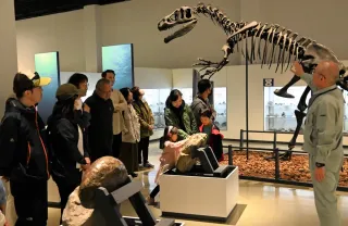 恐竜の骨格標本の解説をする加納館長（右）とツアーの参加者