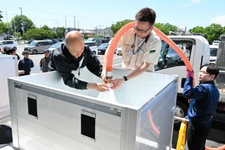 根室市役所前の臨時給水場に飲用水を補充する関係者=7月25日