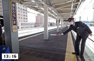 北広島駅に到着。観戦帰りの混雑に対応するため、ホームは延伸された。右は日本ハムのファンという小島英司駅長