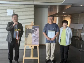 高橋館長(左)から記念品を受け取った来館3千人目の鈴木夫妻