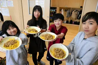 こしみず納豆ジャージャー麺を手に笑顔を見せる小清水小6年の児童
