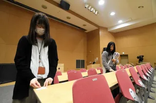 北海道大学の試験会場で、机に受験番号のシールを貼る職員
