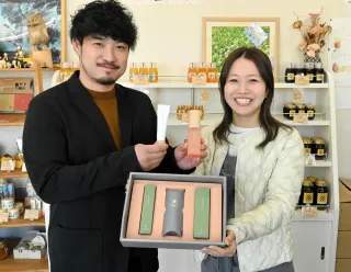 オリジナルの化粧水と保湿バーム、ギフトセットを手にする十勝養蜂園の斉藤達也社長（左）と妻の純さん