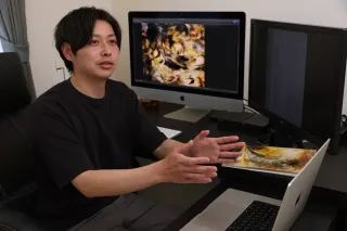 制作に使用しているパソコンとともに、受賞の喜びを語る新堀さん（加藤哲朗撮影）
