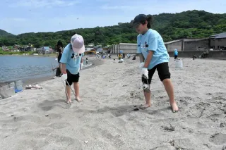 砂浜に落ちたごみを拾う子どもたち
