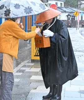 僧侶像 大きな袋を持つ 助け合う心、浄財に感謝 檜山の曹洞宗若手僧侶、江差で托鉢＜師走点描