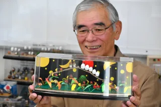 ドングリに着色してホタルやシマエナガに仕上げた作品を手にする米塚貞男さん